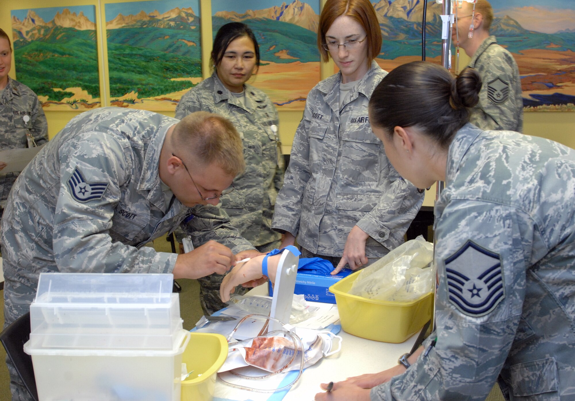 U.S. Air Force Airmen of the 366th Medical Group watch Staff Sgt. Samuel Scott, 366th Surgical Squadron, prepare a training aide for an intravenous drip during the medical Olympics at Mountain Home Air Force Base, Idaho, May 10, 2012. The Olympics which were one activity  held in conjunction with National Nurses Week which began in 1990 when the American Nurses Association expanded National Recognition Day for Nurses to a week-long observance. (U.S. Air Force photo/Senior Airman Alyssa Wallace)