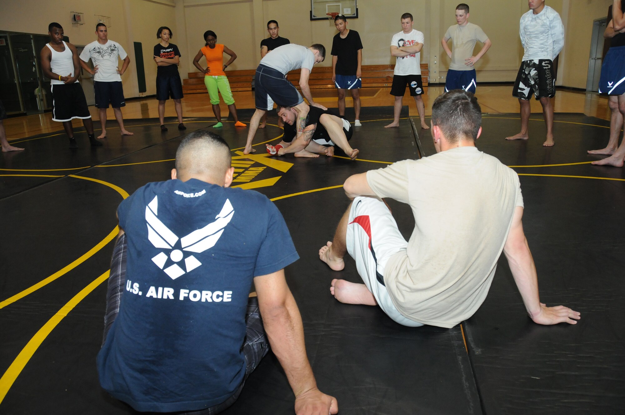 Mike Sanford, professional mixed martial arts instructor from the Alan Belcher MMA Club, assists Alan Belcher in a demonstration of a basic Brazilian Jiu Jitsu move at a single Airman MMA Bootcamp May 10, 2012, at the Dragon Fitness Center, Keesler Air Force Base, Miss.  The bootcamp consists of six weeks of training the basics of MMA including Muay Thai boxing, Brazilian Jiu Jitsu, kickboxing and grappling. The bootcamp was made possible by the Air Force Single Airman Programming Initiative.  (U.S. Air Force photo by Kemberly Groue)
