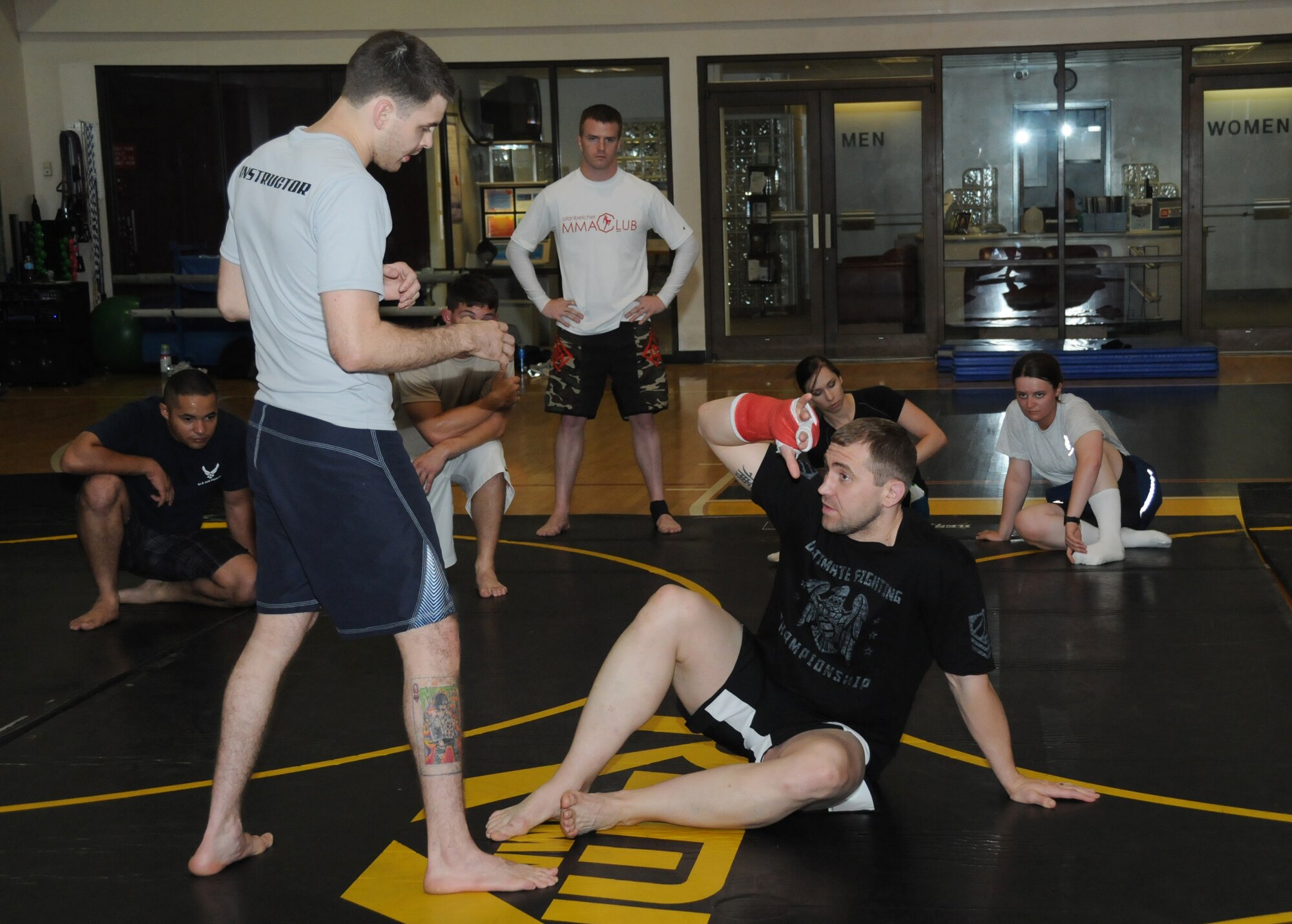 Mike Sanford, professional mixed martial arts instructor from the Alan Belcher MMA Club, assists Alan Belcher in a demonstration of a basic Brazilian Jiu Jitsu move at a single Airman MMA Bootcamp May 10, 2012, at the Dragon Fitness Center, Keesler Air Force Base, Miss.  The bootcamp consists of six weeks of training the basics of MMA including Muay Thai boxing, Brazilian Jiu Jitsu, kickboxing and grappling.  The bootcamp was made possible by the Air Force Single Airman Programming Initiative.  (U.S. Air Force photo by Kemberly Groue)