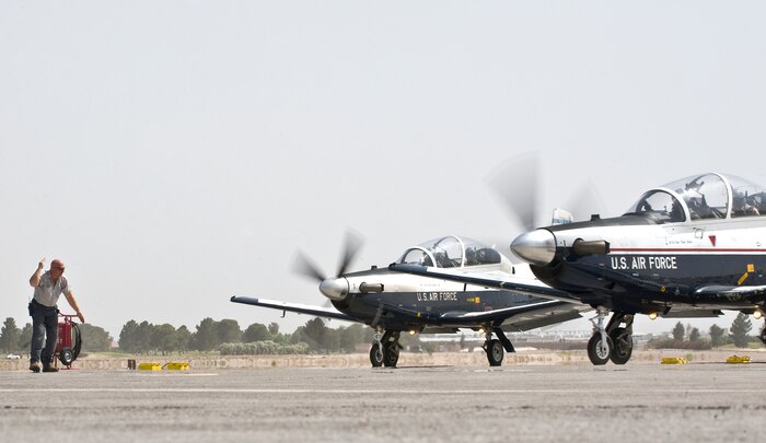 Gary Knouse, Computer Science Corp. flightline expediter, Vance Air Force Base, Okla., marshalls a T-6A Texan II, 33rd Flying Training Squadron, Vance Air Force Base, Okla., during the Weapons Instructor Course May 8, 2012, at Nellis Air Force Base, Nev. The presence of the T-6A Texan II provides another problem set during training  for Mission Commanders during the WIC. (U.S. Air Force photo by Staff Sgt. Christopher Hubenthal)