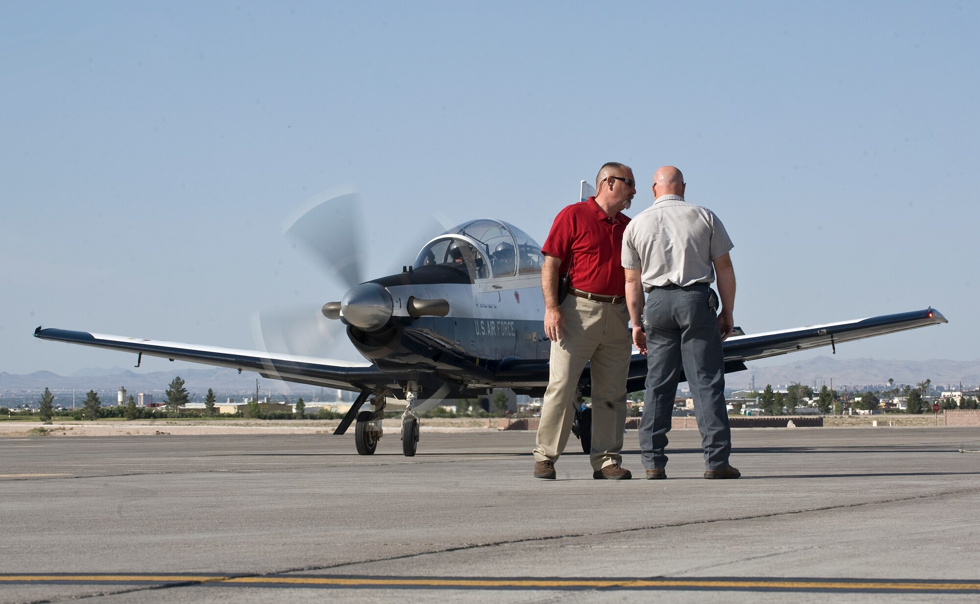 Tim Krienke, Computer Science Corp. flightline supervisor, speaks with Gary Knouse, CSC flightline expediter, prior to the launch of a T-6A Texan II, 33rd Flying Training Squadron, Vance Air Force Base, Okla., May 8, 2012, at Nellis Air Force Base, Nev. The T-6A Texan IIs simulate low flying opposing forces for the Weapons Instructor Course. (U.S. Air Force photo by Staff Sgt. Christopher Hubenthal)
