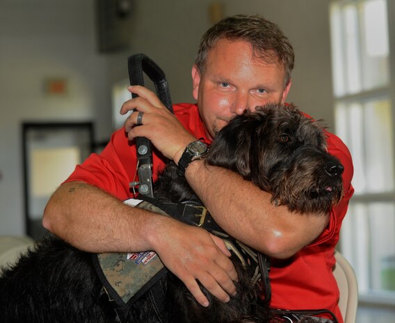 Retired Marine Staff Sgt. Dean Suthard sits with his new service dog, Esther, during a ceremony at the Naval Consolidated Brig Charleston May 9. During the ceremony, NCBC, in partnership with Carolina Canines for Service, presented Suthard, a wounded service member, his service dog. CCFS is a non-profit health and human services organization that trains service dogs for veterans with disabilties. (U.S. Air Force photo/Airman 1st Class Ashlee Galloway)