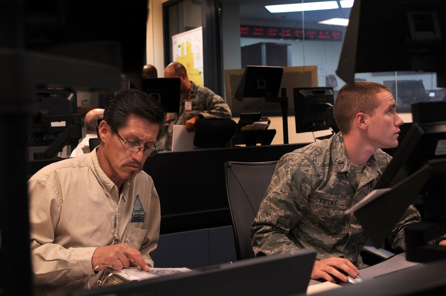 Jake Madril, 27th Special Operations Civil Engineering Squadron solid waste manager, alongside 2nd Lt. Matthew Fecke, 27 SOCES chief of environmental, in the emergency operations center at Cannon Air Force Base, N.M., May 10, 2012. The EOC works as a hub for multiple agencies to respond and make decisions during emergencies. (U.S. Air Force photo by Senior Airman James Bell)