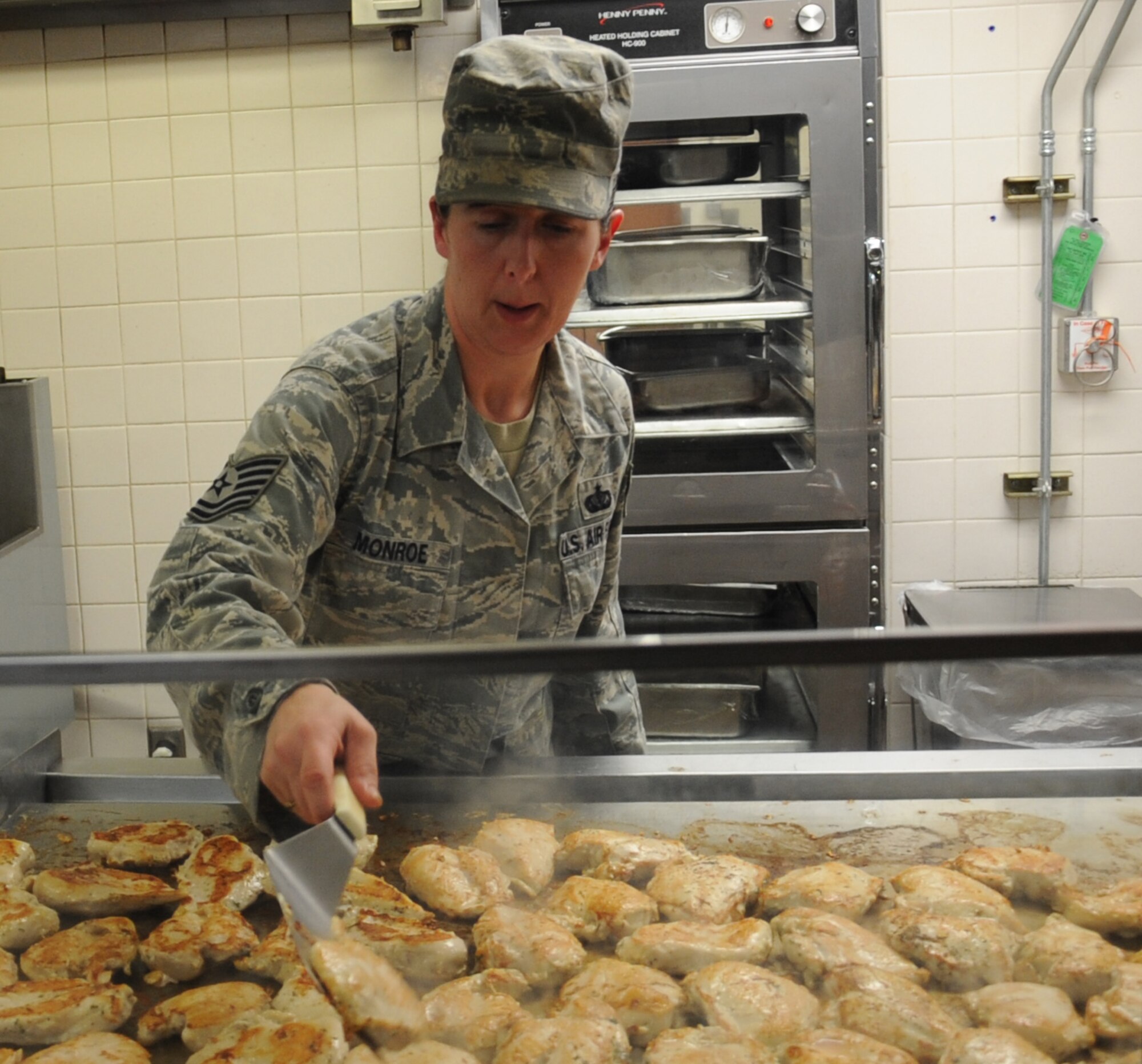 Tech. Sgt. Victoria Monroe, 2nd Force Support Squadron kitchen production manager, prepares chicken breasts at the Red River Dining Facility on Barksdale Air Force Base, La., May 15. The dining facility is available to all military members, officer and enlisted, DoD civilians on TDY or alert status, commanders, squadron section commanders, civilian and military of a foreign government, retirees and their immediate family members, deployed member's immediate family, and anyone in flight operations on official duty. (U.S. Air Force photo/Senior Airman Sean Martin)(RELEASED)
