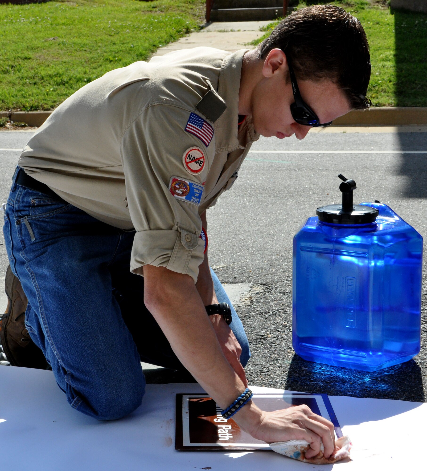 Charles Toplikar Jr., a Boy Scouts of America Troop 31 boy scout, scrubs excess paint from one of his signs for the Air Combat Command running trail May 12. As a marathon runner, Toplikar ran the ACC trail on Langley Air Force Base, Va., often as practice, and became confused at multiple points. Placing the new signs for the trail allows runners to properly assess their distance. (U.S. Air Force photo by Airman 1st Class Austin Harvill/Released) 