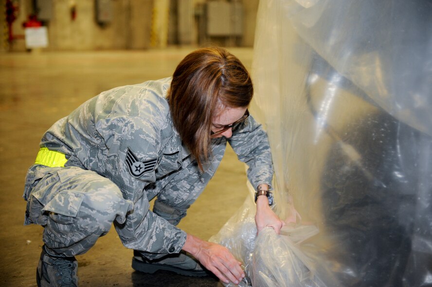 U.S. Air Force Staff Sgt. Hilary Waite, 18th Maintenance Operations Squadron, tucks plastic wrapping underneath a sand bag to cover a vehicle during local operational readiness exercise Beverly High 12-4 on Kadena Air Base, Japan, May 15, 2012. Kadena’s Airmen use LOREs to test themselves in the ability to survive and operate (ATSO) under various conditions. (U.S. Air Force photo/Airman 1st Class Hailey R. Davis)