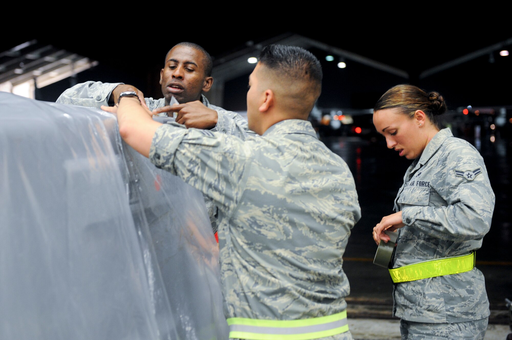 U.S. Air Force Staff Sgt. Conray Brown, U.S. Air Force Senior Airman Christopher Reschman and U.S. Air Force Airman 1st Class Quincey Bergeron, 18th Maintenance Operations Squadron, secure M8 paper with duct tape onto a vehicle during local operational readiness exercise Beverly High 12-4 on Kadena Air Base, Japan, May 15, 2012. LOREs give Airmen the opportunity to practice readiness skills and prepare for real-world contingencies. (U.S. Air Force photo/Airman 1st Class Hailey R. Davis)