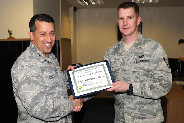 RAF ALCONBURY, United Kingdom - Col. Brian Kelly, 501st Combat Support Wing commander, presents the Innovator of the Month Award to Tech. Sgt. Matthew Paxton, 501st CSW Staff. Paxton created a tracking worksheet for all services contracts. This initiative helps save man hours and effort for pre-award actions as well as post-award administration man hours. (U.S. Air Force photo by Senior Airman Joel Mease) 
