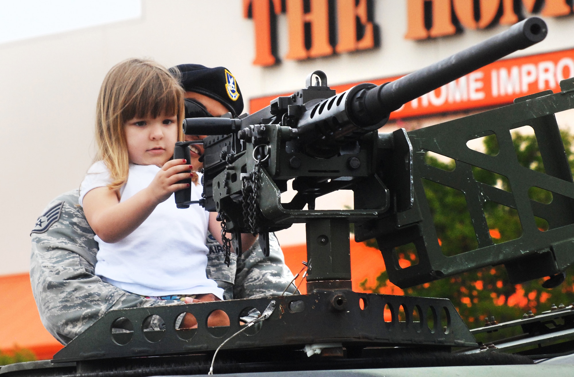 Skylar Horton, 4, gets a boost from Staff Sgt. Jason Balcita, 78th Security Forces Squadron, to get a close look at a 50 caliber gun in the turret of the Humvee displayed for National Police Week Saturday at Home Depot.(U. S. Air Force photo by Sue Sapp)
