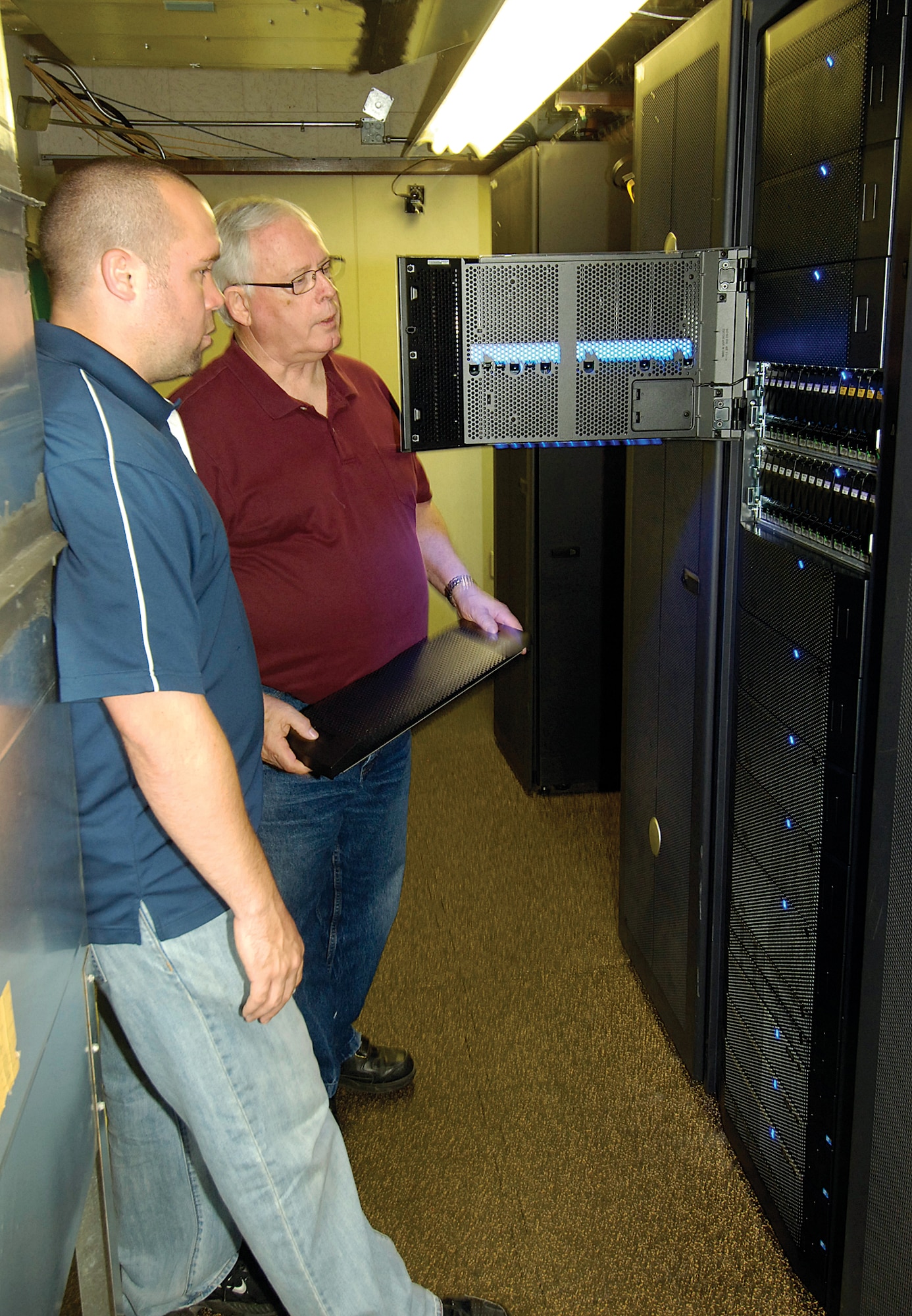 Darren Porter, left, and Hal Sultzbach, both storage area network administrators in the 72nd Air Base Wing Communications Directorate, look at a new system in the Data Center that is saving space and money plus increasing data storage efficiency for thousands of Tinker personnel.  At two-feet wide, roughly half the size of its predecessor, the storage system still holds more information but takes up less space and uses less electricity.  According to Mr. Sultzbach, after the new system was installed, energy consumption was nearly cut in half. (Air Force photo by Margo Wright)