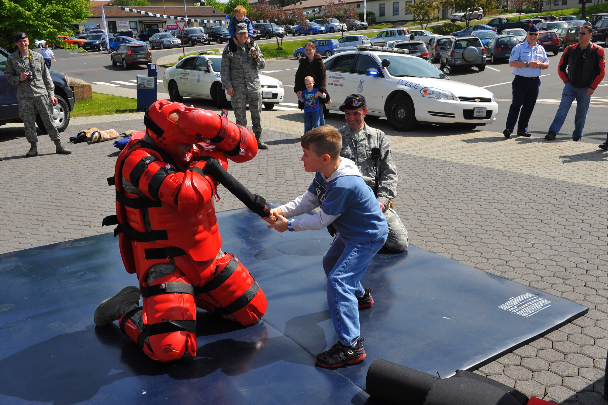 SPANGDAHLEM AIR BASE, Germany – Joshua Thompson, son of Chaplain (Maj.) Daniel Thompson, 52nd Fighter Wing Chapel, hits Senior Airman Adam Crane, 52nd Security Forces Squadron trainer, during a combatives training demonstration for National Police Week outside the Spangdahlem Commissary May 14. The 52nd SFS put on multiple demonstrations such as military working dog capabilities, weapons and combat vehicle displays and taser demonstrations to give spectators an insight into various aspects of security forces capabilities. National Police Week is held annually during the week of May 15 and honors all law enforcement members who have died. National Police Week events continue this week with an annual ruck march around the base May 16 at 10 a.m. and the defender decathlon May 17 beginning at 9 a.m. on Perimeter Road here. (U.S. Air Force photo by Airman 1st Class Dillon Davis/Released)