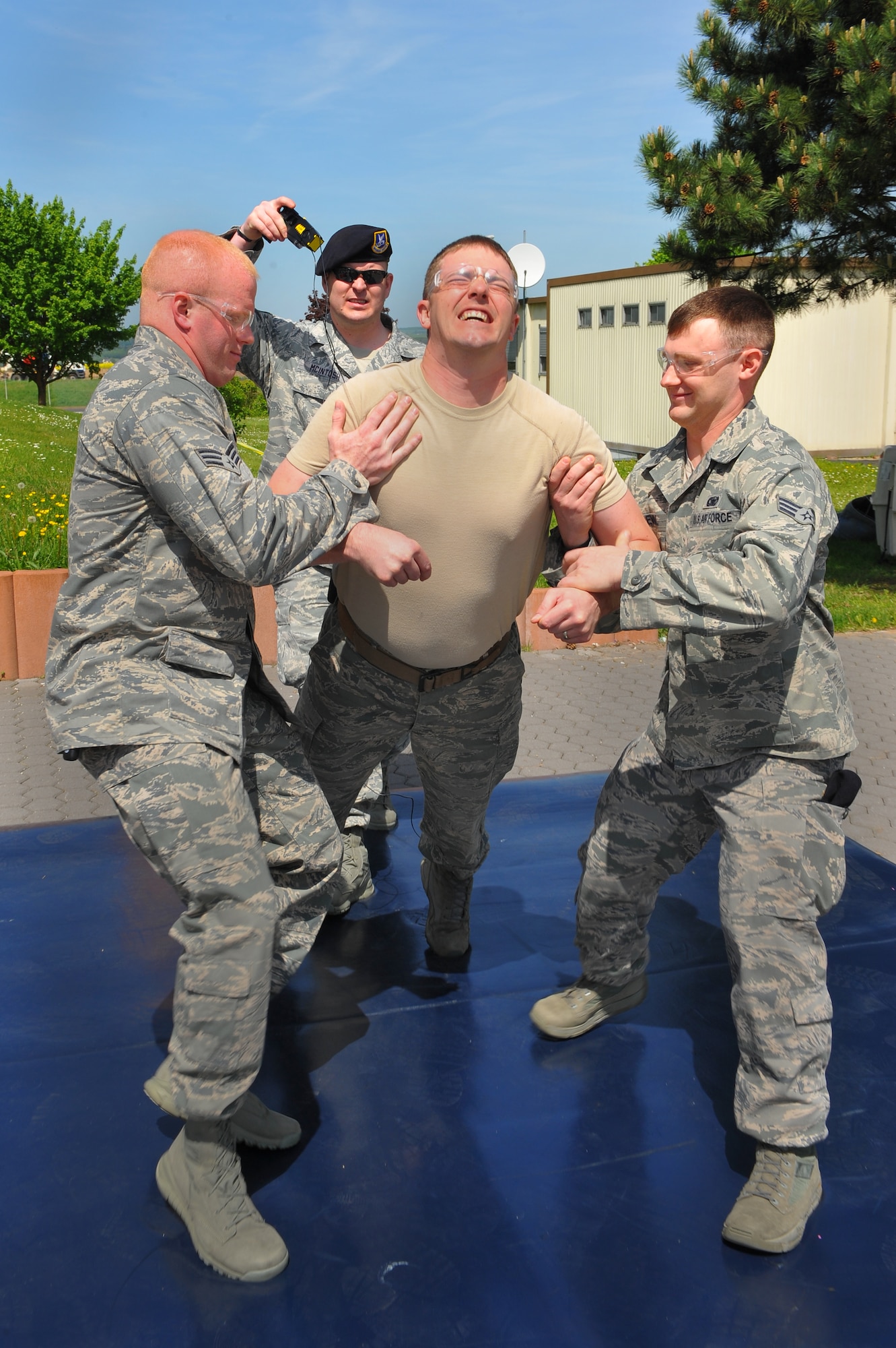 SPANGDAHLEM AIR BASE, Germany – Senior Airman Jod Nicholson, center, 52nd Security Forces Squadron patrolman, clenches while being tazed during a non-lethal weapons demonstration for National Police Week outside the Spangdahlem Commissary May 14. The 52nd SFS put on multiple demonstrations such as military working dog capabilities, weapons and combat vehicle displays and taser demonstrations to give spectators an insight into various aspects of security forces capabilities. National Police Week is held annually during the week of May 15 and honors all law enforcement members who have died. National Police Week events continue this week with an annual ruck march around the base May 16 at 10 a.m. and the defender decathlon May 17 beginning at 9 a.m. on Perimeter Road here. (U.S. Air Force photo by Airman 1st Class Dillon Davis/Released)