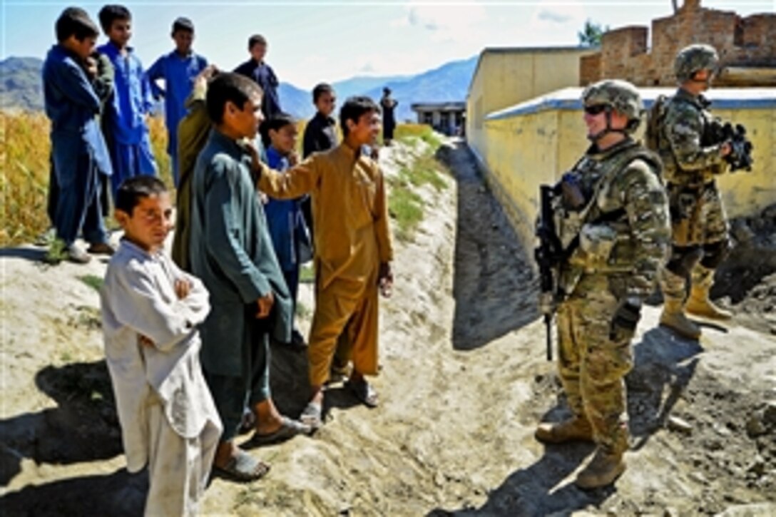 U.S. Navy Cmdr. Michael Yesunas chats with children while members of Provincial Reconstruction Team Kunar conduct quality checks and speak to residents as part of a patrol in Afghanistan's Kunar province, May 12, 2012. Yesunas, a naval helicopter pilot, is the team's commander.