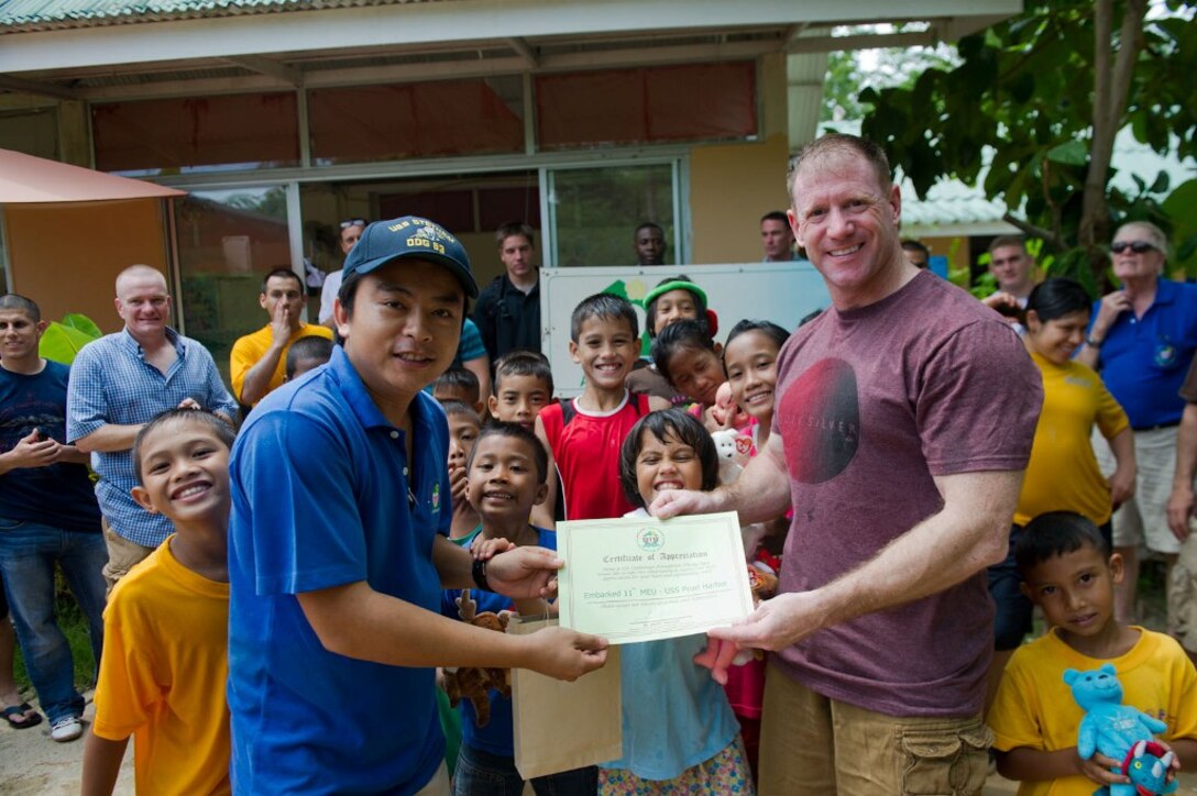 First Sgt. Michael P. Edwards, right, accepts a letter of appreciation here May 15 after he and other Marines serving with the 11th Marine Expeditionary Unit shoveled dirt during a volunteer project at an orphanage. Edwards hails from Rome, N.Y., and serves as first sergeant for Battery K, Battalion Landing Team 3/1. The landing team serves as the ground combat element for the 11th Marine Expeditionary Unit, which embarked the ship, as well as USS Makin Island and USS New Orleans in San Diego Nov. 14, beginning a seven-month deployment to the Western Pacific, Horn of Africa and Middle East regions.