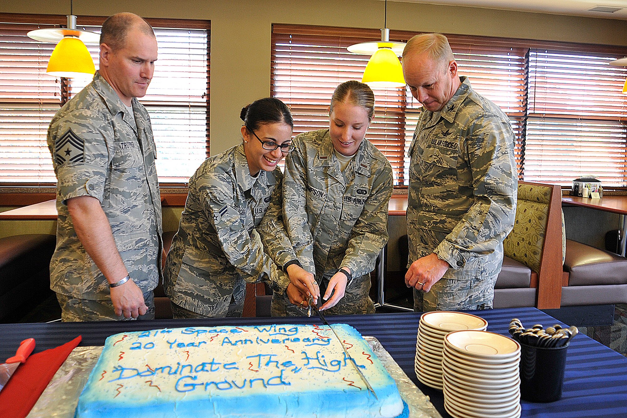 PETERSON AIR FORCE BASE, Colo. – (Left to right) Chief Master Sgt. Thomas Trottier, the 21st Space Wing command chief; Airman 1st Class Emily Alicea and 2nd Lt. Kayleigh Thompson, both of the 21st Force Support Squadron; and Col. Chris Crawford, the 21st SW commander, cut a cake in celebration of the 20th anniversary of the wing in the Aragon Dining Facility May 15, 2012. Alicea is the youngest Airman in the 21st SW. (U.S. Air Force photo/Dennis Howk)