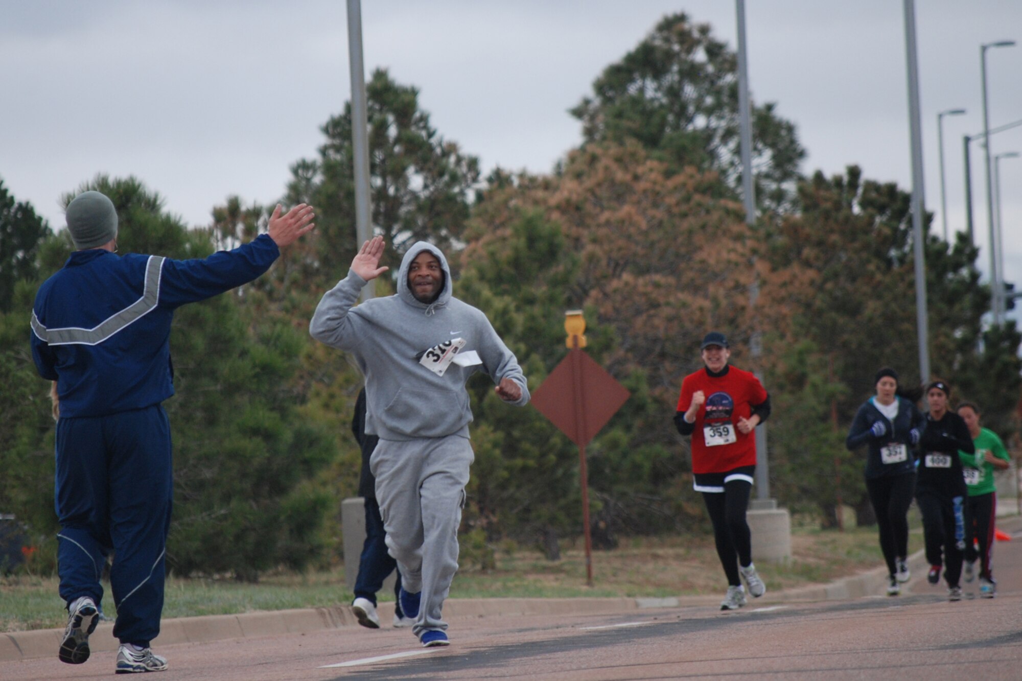 PETERSON AIR FORCE BASE, Colo. -- Tyrone Barney high-fives an on-looker during the last portion of the Armed Forces Day Community Run held on base May 12, 2012. The 200 participants braved the cold, damp weather for this annual event, which was open to all members of the community. (U.S. Air Force photo/Tech. Sgt. Amanda Callahan)