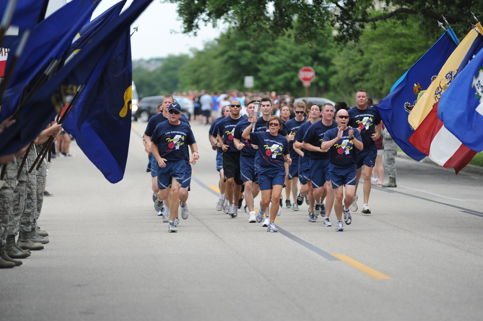 Keesler Airmen hold the 50 state flags steady as Brig. Gen. Andrew Mueller, 81st Training Wing commander, Chief Master Sgt. Angelica Johnson, 81 TRW command chief, and Col. Glen Downing, 81 TRW vice commander, run the “Flame of Hope” down Phantom Street accompanied by runners from the 81st Security Forces Squadron in preparation for the Special Olympics Mississippi Summer Games, May 11, 2012, at Keesler Air Force Base, Miss. It’s the 26th year that Keesler has hosted the statewide event. Opening ceremonies took place May 11. Athletic competitions took place throughout the day and were followed by a victory dance May 12. More than 1,200 athletes and coaches and 3,000 volunteers joined forces to make the event a success.  (U.S. Air Force photo by Kemberly Groue)