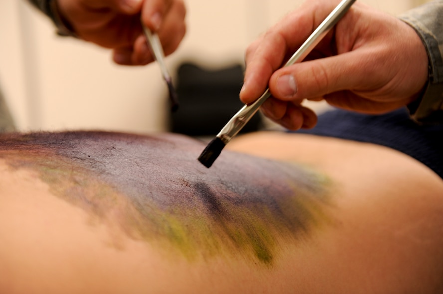 U.S. Air Force Tech. Sgt.  Alan Blair, 18th Component Maintenance Squadron propulsion craftsman, and U.S. Air Force Master Sgt. John Stott, 18th Wing superintendent of plans and programs, apply moulage makeup to a simulated victim prior to a training scenario during local operational readiness exercise Beverly High 12-4 on Kadena Air Base, Japan, May 16, 2012. The LORE is conducted to test the base's ability to defend Japan and maintain peace and stability in the Pacific region. (U.S. Air Force photo/ Airman 1st Class Brooke P. Beers)