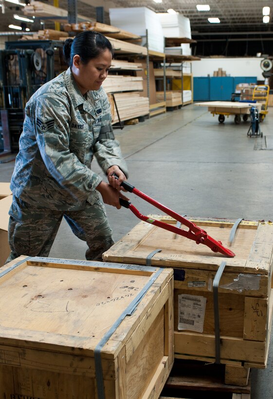 Senior Airman Joyce Dayrit, 28th Logistics Readiness Squadron supply technician, cuts metal bands off of crates using a band cutter during a package inspection at Ellsworth Air Force Base, S.D., May 8, 2012. These packing bands ensure cargo remains safely sealed during shipment. (U.S. Air Force photo by Airman 1st Class Alystria Maurer/Released)