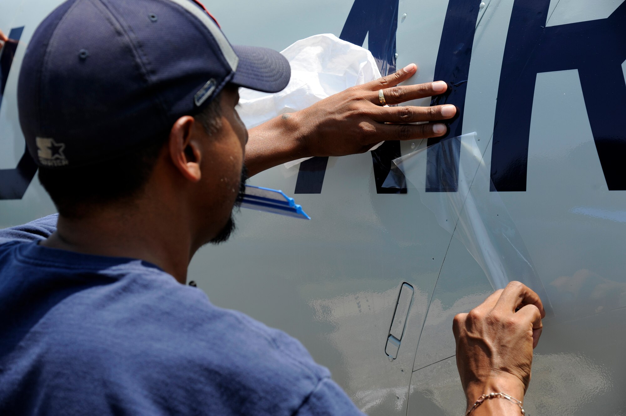 A maintainer from the 47th Maintenance Directorate’s Corrosion Control section smoothes out bubbles formed under a newly applied decal to the body of the T-33 Shooting Star jet trainer on display at Laughlin Air Force Base, Texas, May 7, 2012. The corrosion control section sets aside a month each year to clean and repair the 11 static aircraft that populate Laughlin’s landscape. (U.S. Air Force photo/Airman 1st Class Nathan Maysonet)
