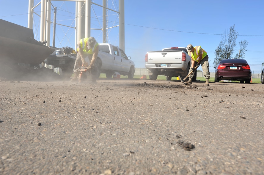MINOT AIR FORCE BASE, N.D. -- Airman 1st Class Cody Waymire , 5th Civil Engineer Squadron heavy equipment operator, uses a K-12 concrete saw to cut around the damaged concrete while Airman 1st Class Zachary Flowers, 5th CES heavy equipment operator, uses a maddox to break up the concrete during a routine road fixture project here May 10. (U.S. Air Force photo/Senior Airman Brittany Y. Auld)