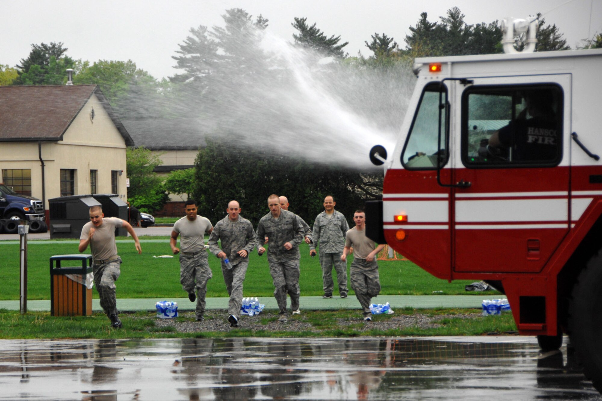 HANSCOM AIR FORCE BASE, Mass. – Airmen try to avoid water spraying from a fire truck during Warrior Day May 9. In addition to running through water, some Airmen from the 66th Air Base Group ran around the track, carried heavy weights and participated in many more team-building activities. (U.S. Air Force photo by Linda LaBonte Britt)
