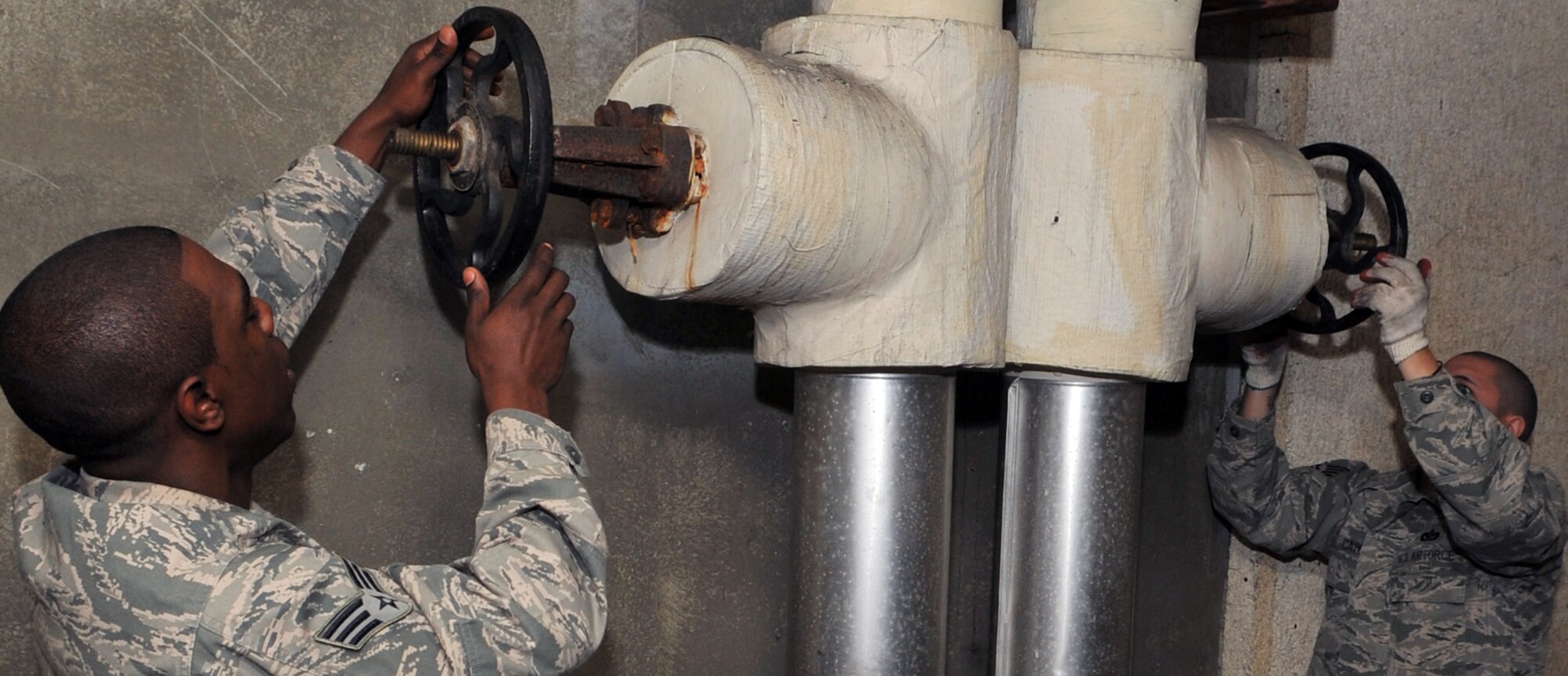 Senior Airman Devin McCree and Staff Sgt. Michael Cato, both 51st Civil Engineer Squadron heating, ventilation, and air conditioning technicians, open valves to allow water to reach  the air conditioning chillers at Osan Air Base, Republic of Korea, May 16, 2012. The water cannot exceed 72 degrees Fahrenheit, before the valves can be opened. (U.S. Air Force photo/Staff Sgt. Craig Cisek)