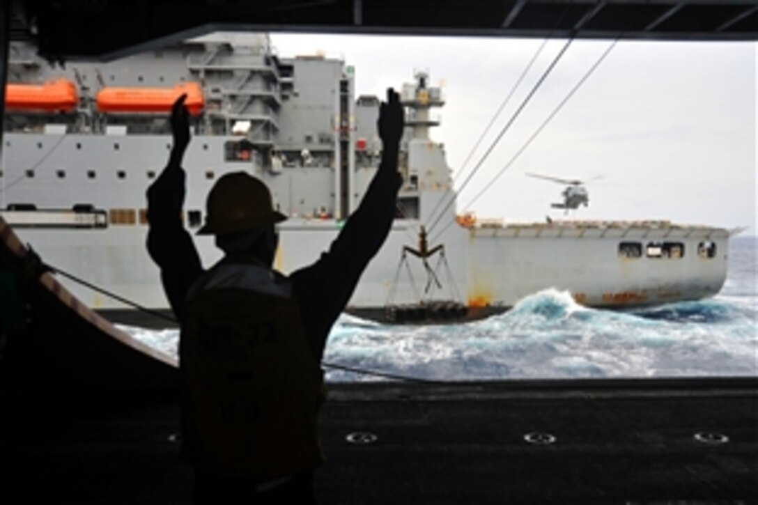 U.S. Navy Petty Officer 3rd Class Ebrima Jagne signals the distance of an ammunition load aboard the aircraft carrier USS George Washington during a replenishment-at-sea mission in the Pacific Ocean, May 15, 2012. The George Washington successfully completed a six-month, routine maintenance period and is now underway conducting sea trials. 