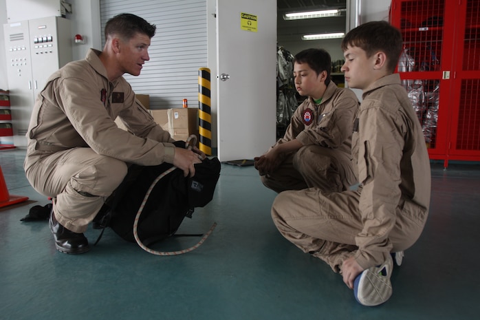 Sgt. Bruce L. Best, station Aircraft Rescue Firefighting assistant section 2 leader, discusses the different equipment used by ARFF Marines when they may have to rescue someone on a mountain to Joey Beall (front), Matthew C. Perry seventh-grader, and William Eaglin, M. C. Perry eighth grader, during a job shadow day at the ARFF fire house here May 17, 2012. The students spent the day following ARFF Marines as they went about the daily routine involved with being ARFF Marines.