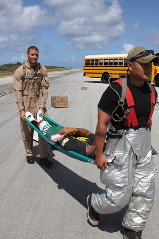 Cpl. Christopher M. Perry, an Aircraft Rescue Firefighter with Marine Wing Support Squadron 171, Marine Aircraft Group 12, and a Tinian firefighter carry simulated injury victims to a staging area during an evaluation for the Tinian firefighters. The Marines were participating in Exercise Geiger Fury 2012 and offered their services to their local counterparts.
