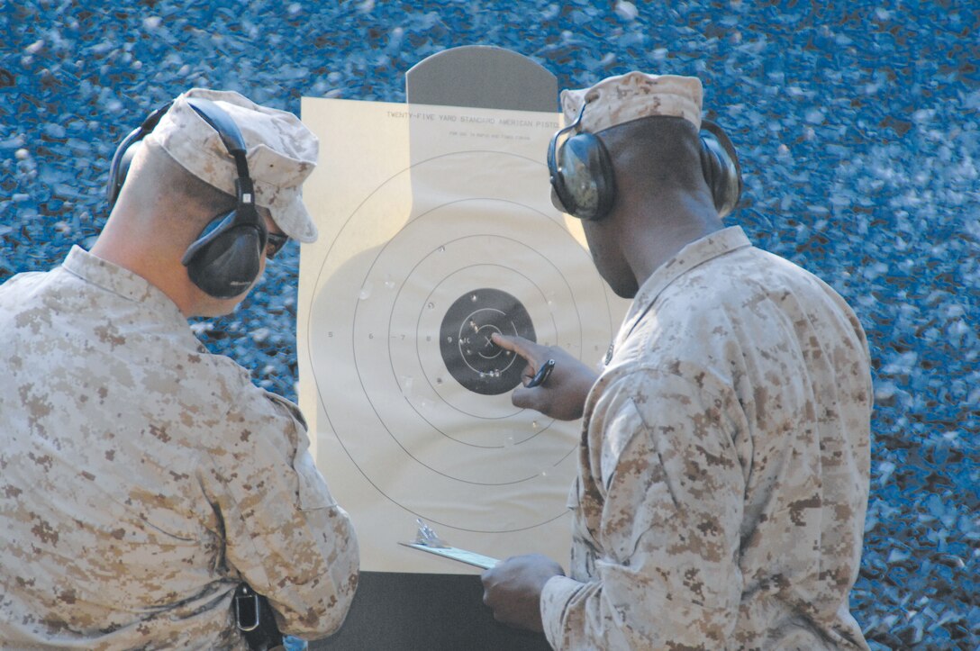 Gunnery Sgt. Kejuan Hull checks his score on his target during pistol qualification at the newly upgraded Recreational Pistol Range, recently, as another Marine watches.