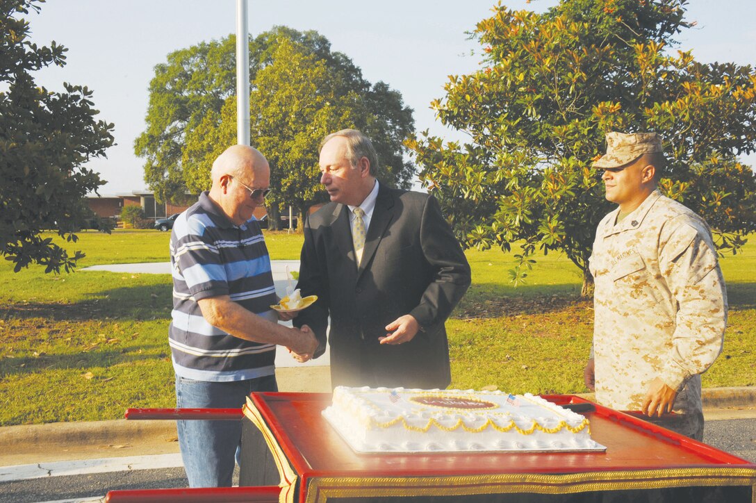 Michael T. Madden, executive deputy, MCLC, gives the first piece of birthday cake to the oldest plank holder, Robert "Don" Golden, a management and program assistant, MCLC, and a retired Marine Corps master gunnery sergeant. Golden began working here in 1981 and was part of MCLC's activation ceremony in May 2003