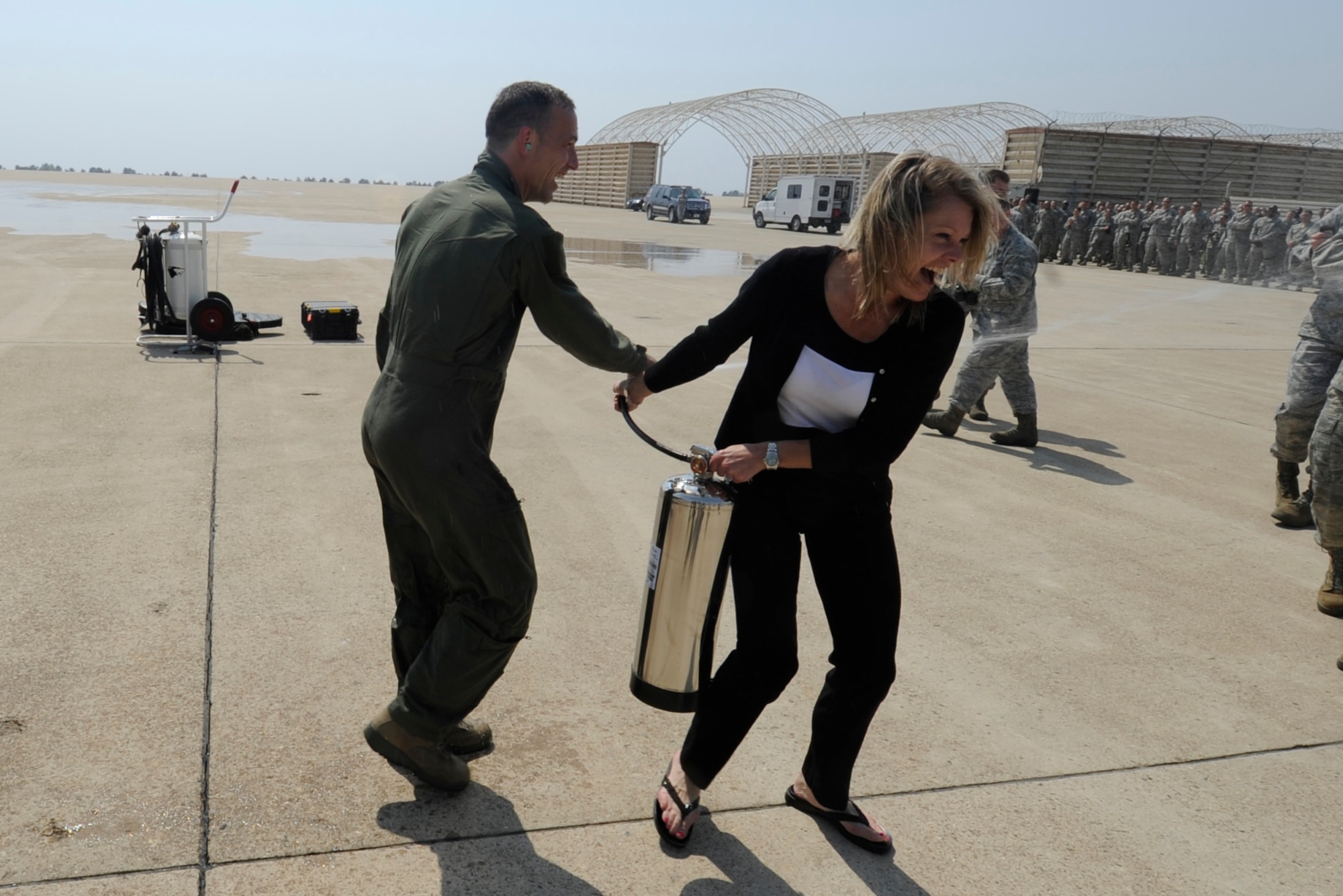 Col. Scott L. Pleus, 8th Fighter Wing commander, attempts to take a water sprayer from his wife, Jennifer Pleus, to spray water at his group commander standing close by after his final flight as the wing commander of the Wolf Pack on Kunsan Air Base, Republic of Korea, May 16, 2012. (U.S. Air Force photo/Senior Airman Jessica Hines)