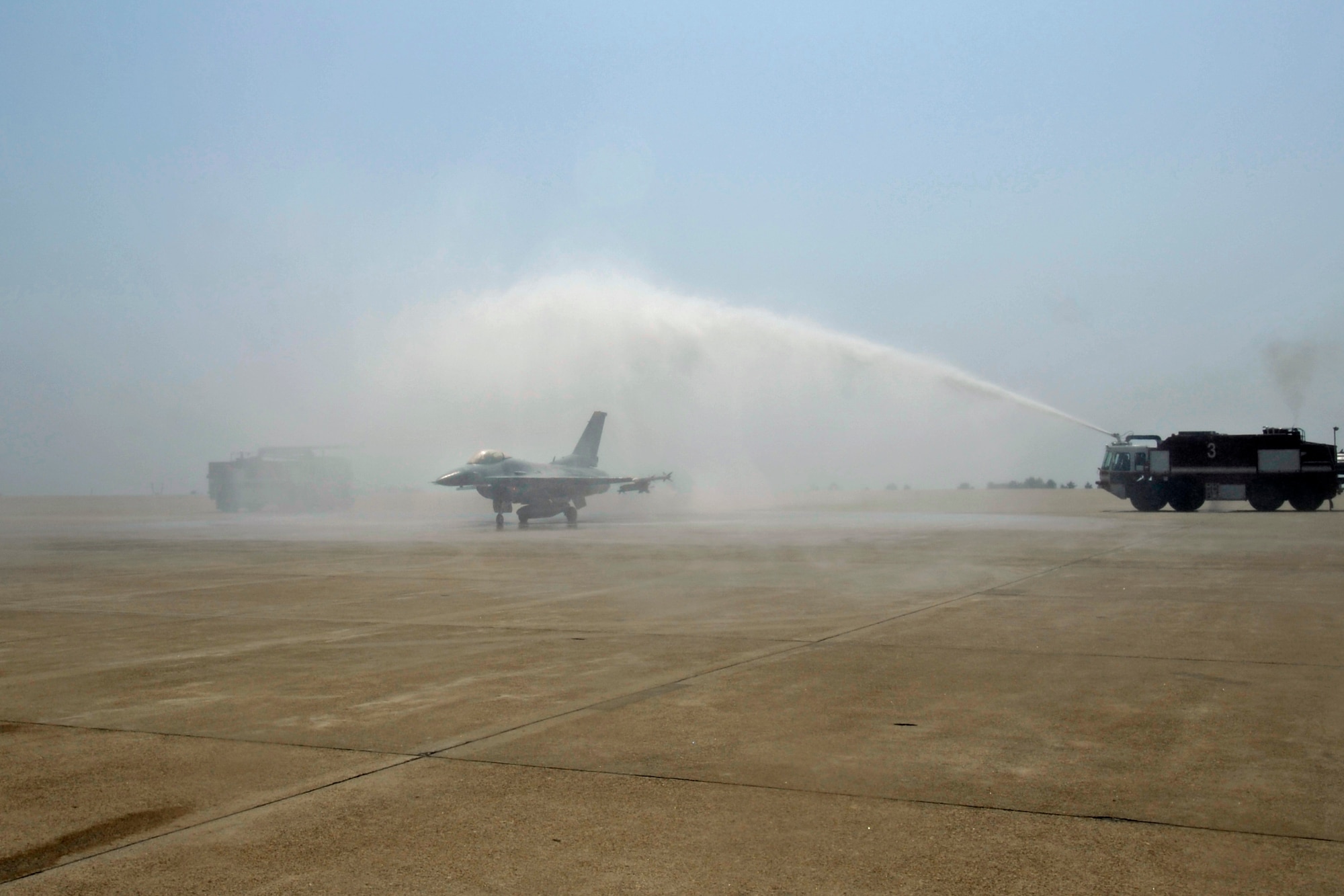 Col. Scott L. Pleus, 8th Fighter Wing commander, taxis between two fire trucks after his final flight as the wing commander of the Wolf Pack on Kunsan Air Base, Republic of Korea, May 16, 2012. It's traditional for fire trucks to join the crowd in welcoming the pilot back from his final flight with a unit (U.S. Air Force photo/Senior Airman Jessica Hines)