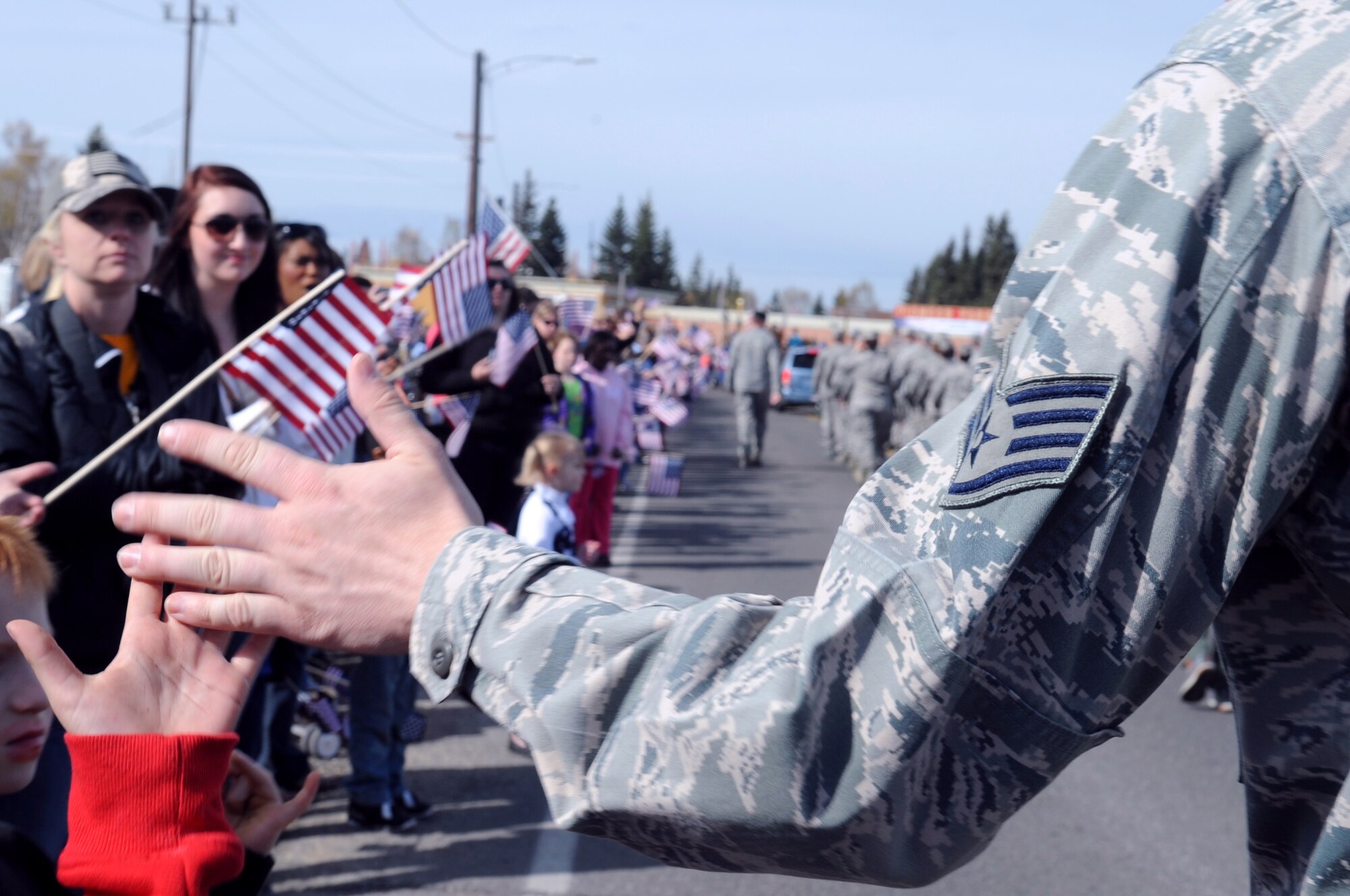 A U.S. Air Force Airman from Eielson Air Force Base high-fives a child during the Salute to Our Military Parade May 12, 2012, Fairbanks, Alaska. Thousands of Alaskans gathered for the event, aimed at honoring local military members. (U.S. Air Force photo/Airman 1st Class Lauren-Taylor Garcia)