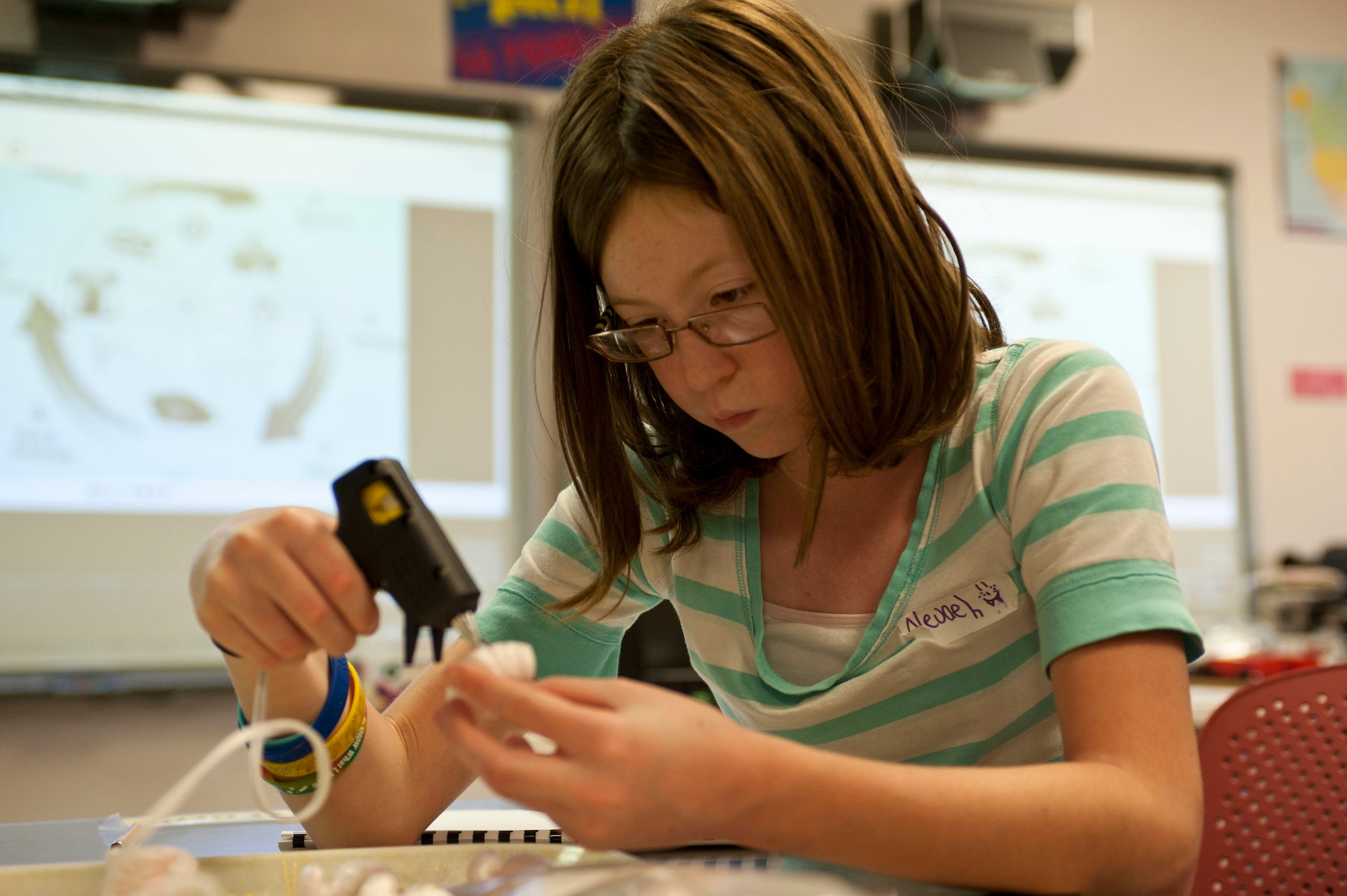 Nevaeh Williams,10, uses a hot glue gun to construct a bridge out of popsicle sticks, styrofoam peanuts and dried lasagna pasta May 10, 2012, at Nellis Air Force Base, Nev. The science experiment is used to help students understand buoyancy.  (U.S. Air Force photo/Airman 1st Class Jason Couillard)