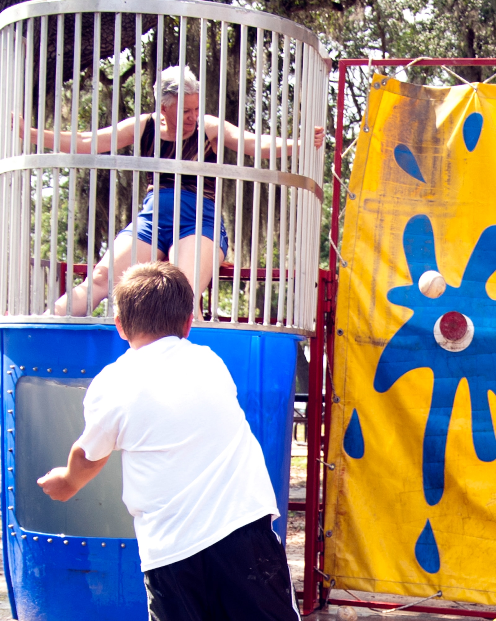 Col. Anna Schulte, 403rd Maintenance Group commander, waits to see if the softball thrown by Ethan McCraine, son of Maj. Rodney McCraine, hits the target to plunge her into the water during the 403rd Wing's Family Day event May 5. (U.S. Air Force photo illustration by Maj. Heather Newcomb)