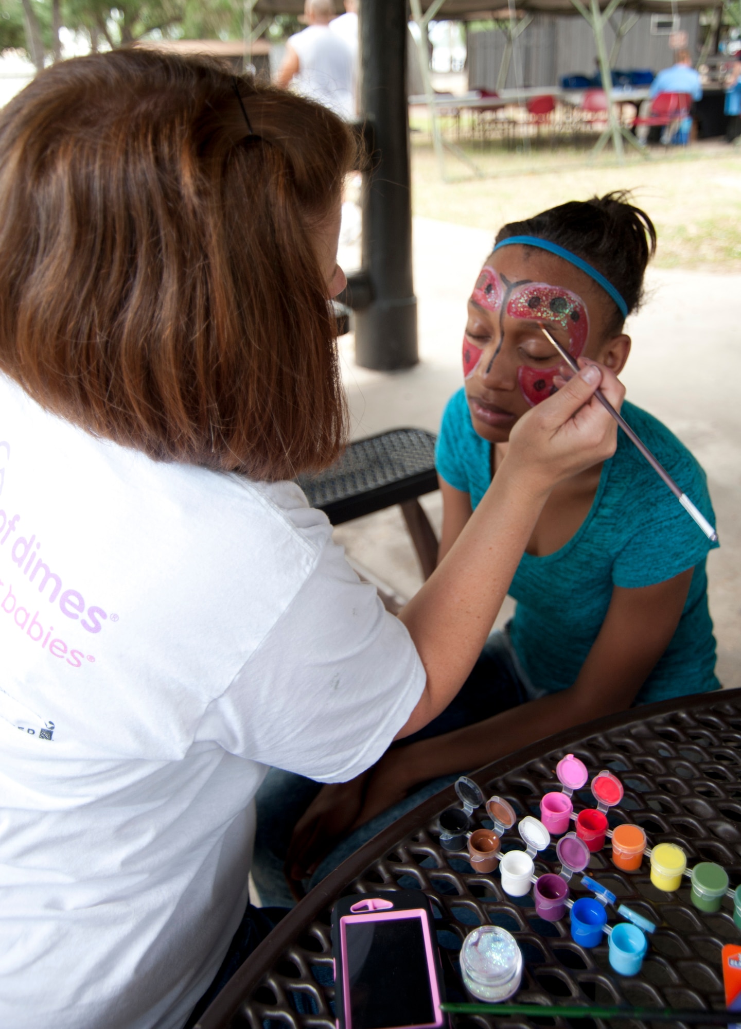 Jayla Sims, family member of Master Sgt. Paula Bullock, has her face painted by Tech. Sgt. Debra Gentry, during the 403rd Wing's Family Day event May 5. (U.S. Air Force photo illustration by Maj. Heather Newcomb)