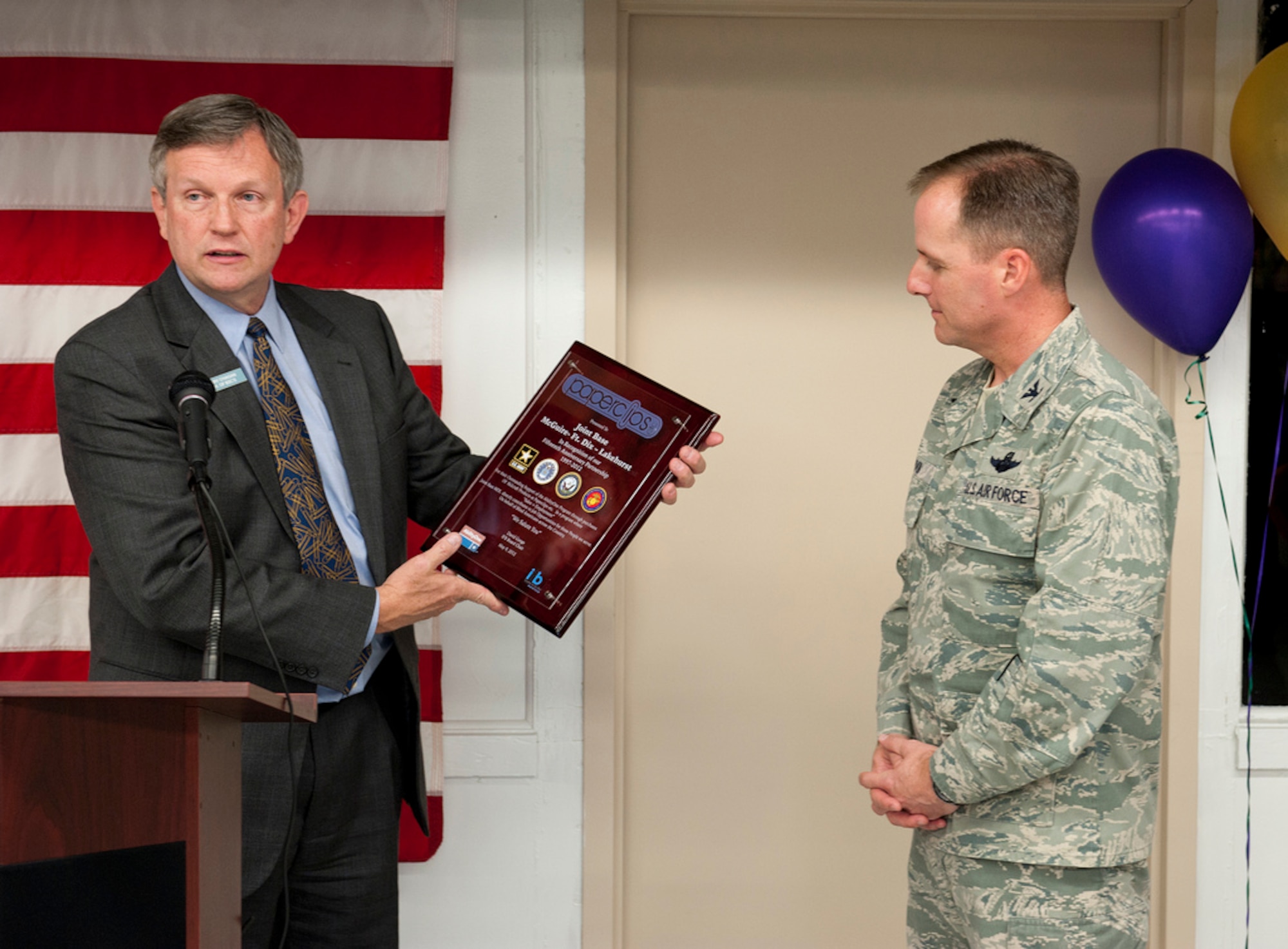 Jerry O'Hagan, Director of Base Supply Centers, Industries for the Blind Winston-Salem, presents Col. John Wood, 87th Air Base Wing commander, a plaque in recognition of the 15-year partnership with Joint Base McGuire-Dix-Lakehurst from 1997 through 2012, at Paperclips May 9 here. Various vendors were on hand for the customer appreciation event. Winston-Salem Industries for the Blind provides opportunities for persons who are visually impaired in need of training, employment and services. They maintain a minimum of 75 percent of their entire workforce as visually impaired. (U.S. Air Force photo by Russ Meseroll/Released)