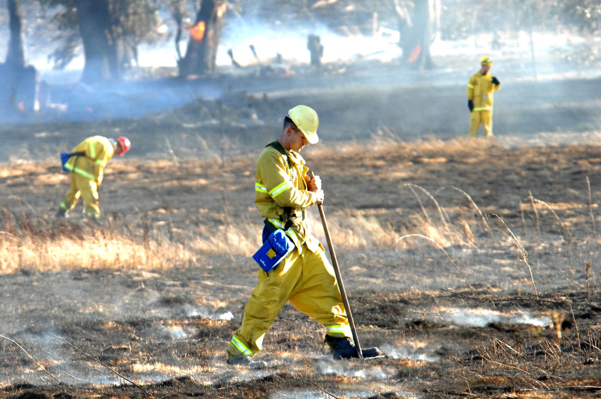 Fire fighter Senior Airman Adam Foret of the  60th Civil Engineering Squadron knocks down flame flare-ups after the Travis Fire Department team extinguished a grass fire on Saturday Oct. 4, 2008, on the base. (U.S. Air Force  photo/Nan Wylie)