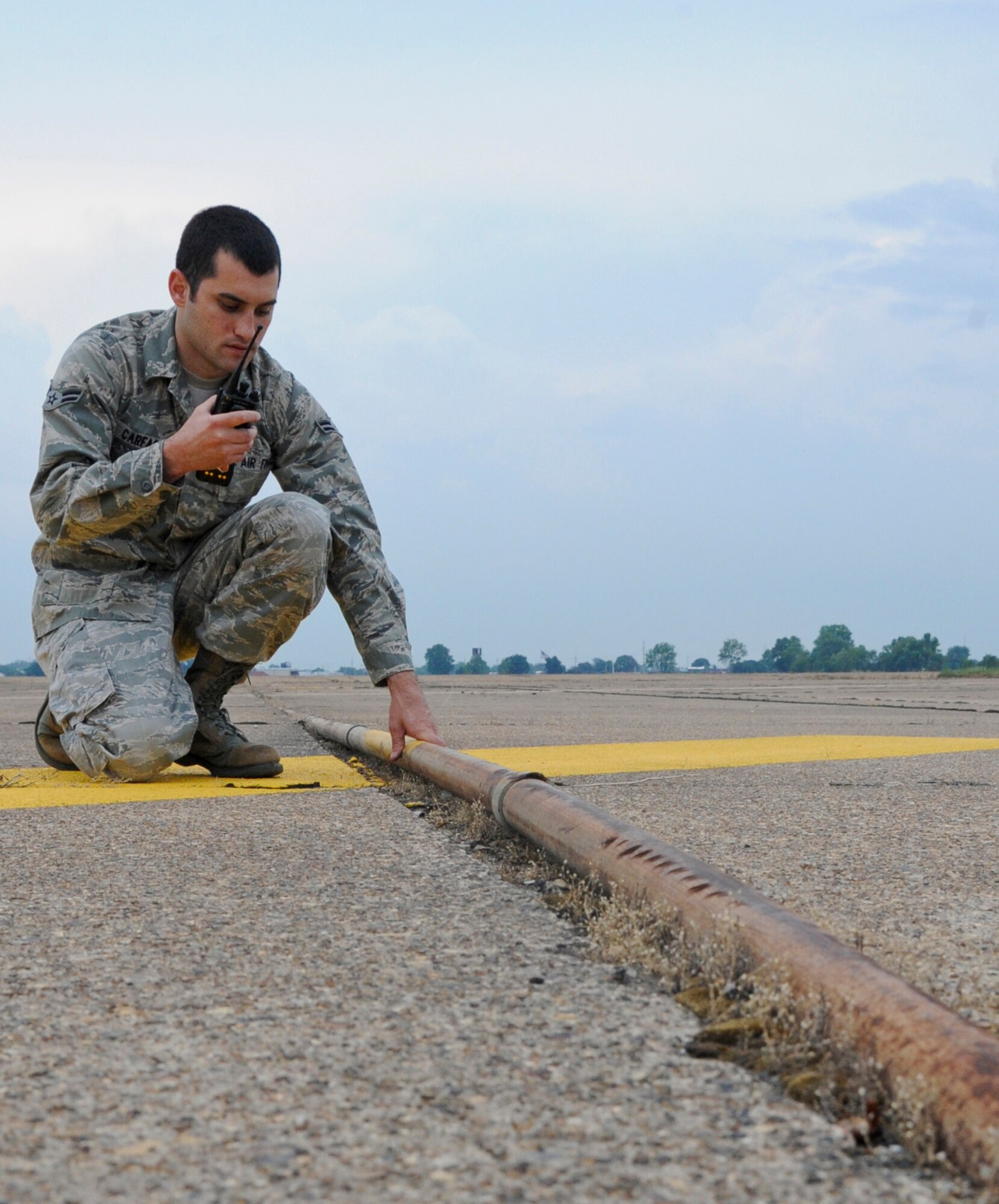 Airman 1st Class Mario Carfagno III, 2nd Operations Support Squadron airfield manager, calls in a damage report to the Airfield Management office on Barksdale Air Force Base, La., May 15. The pipe was pushed up from the runway due to changing temperatures causing the concrete to expand and contract. (U.S. Air Force photo/Airman 1st Class Micaiah Anthony)(RELEASED)