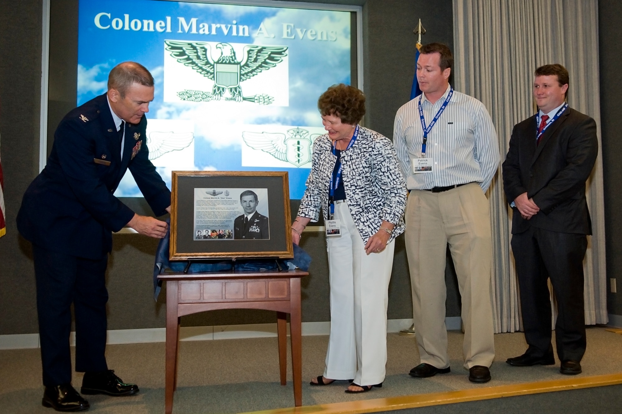 GRISSOM AIR RESERVE BASE, Ind. -- Col. William T. "Tim" Cahoon and Phyllis Evens unveil a memorial lithograph honoring the late Col. (Dr.) Marvin Evens as the Evens' sons, Patrick and Christopher, look on  during a special ceremony in Gus Grissom Hall here May 14. Phyllis Evens is the wife of Colonel Evens, a 930th Medical Group commander and A-10 pilot who lost his life when his A-10 crashed during a training mission near Grissom in 1992. (U.S. Air Force photo/Tech. Sgt. Mark R. W. Orders-Woempner)
