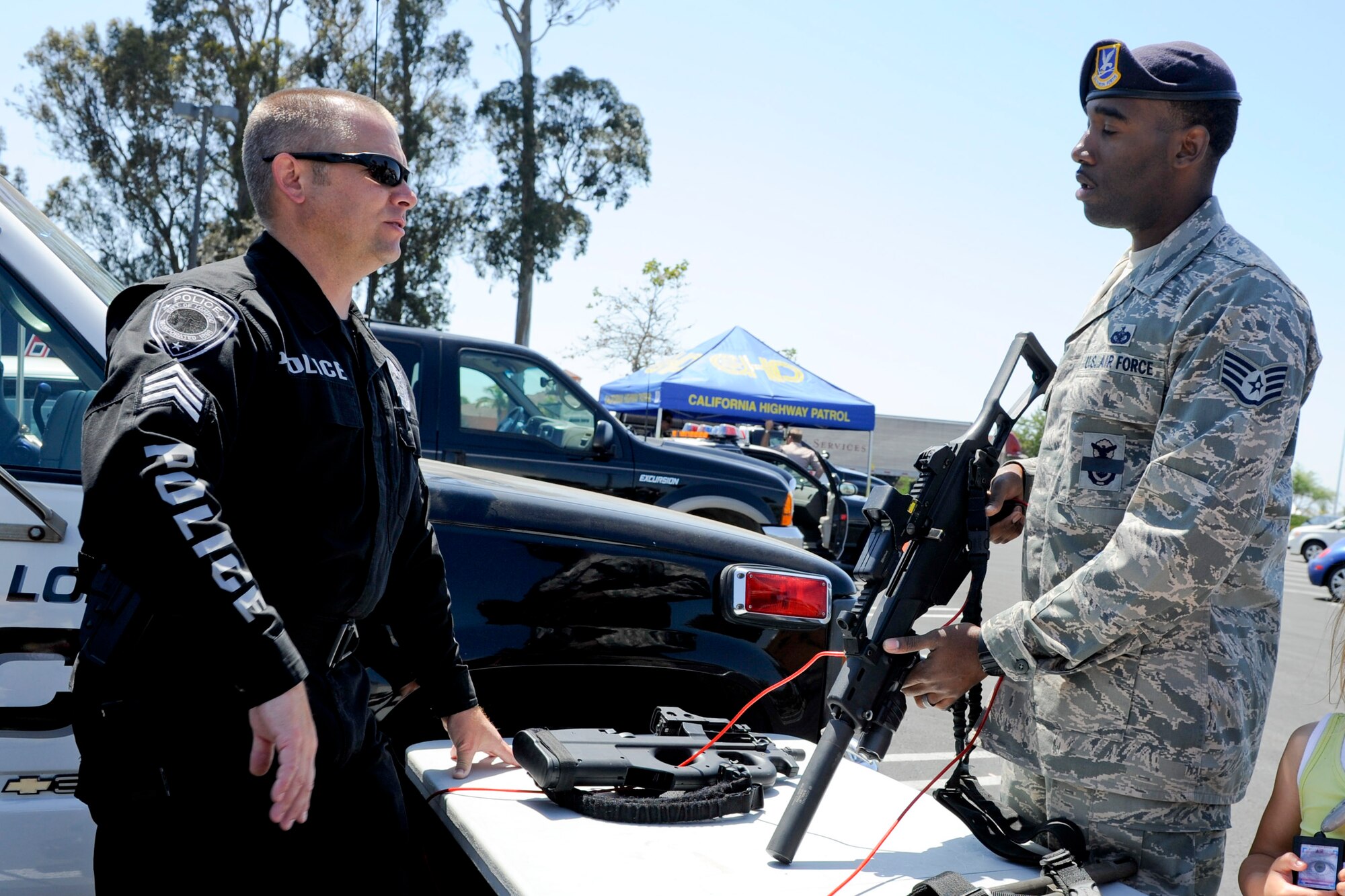 VANDENBERG AIR FORCE BASE, Calif. -- Staff Sgt. Henry Edwards III, a 30th Security Forces Squadron dog handler, talks to a Lompoc Police officer about weapons they use during their daily duties during a police display event at the Albertsons parking lot in Lompoc, Wednesday, May 16th, 2012. The display was held in conjunction with National Police Week, an annual celebration that recognizes the service and sacrifice of U.S. law enforcement personnel. (U.S. Air Force photo/Staff Sgt. Levi Riendeau)