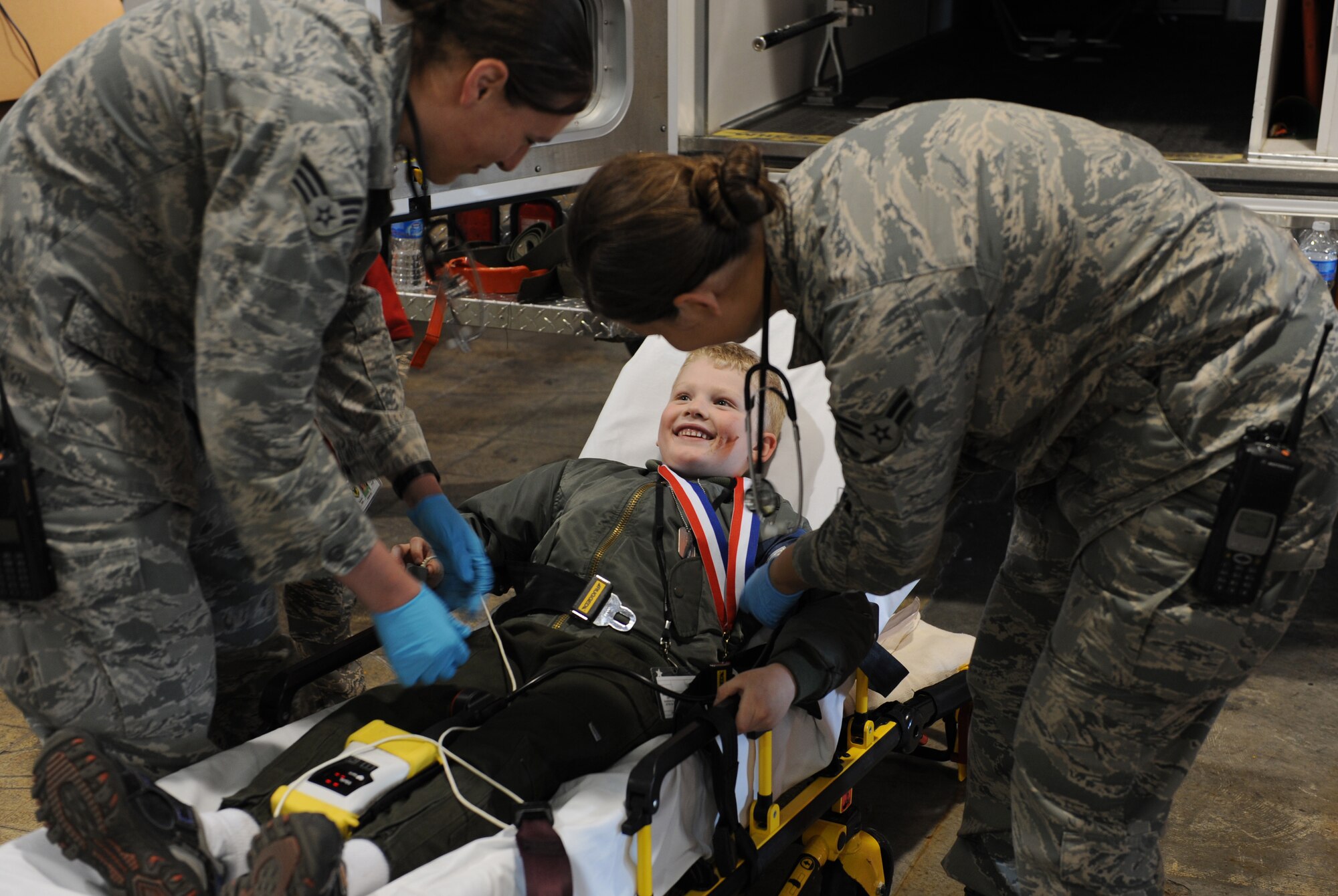 WHITEMAN AIR FORCE BASE, Mo. -- Members of the medical group simulate strapping a child in a stretcher during the “tent city” portion of Operation Spirit at the Deployment Center April 21. After a morning of deploying the participants visited “tent city” where they viewed equipment and viewed demonstrations from different base agencies to include explosive ordinance disposal, security forces, fire department and medical group. (U.S. Air Force photo/Airman 1st Class Bryan Crane)(Released)