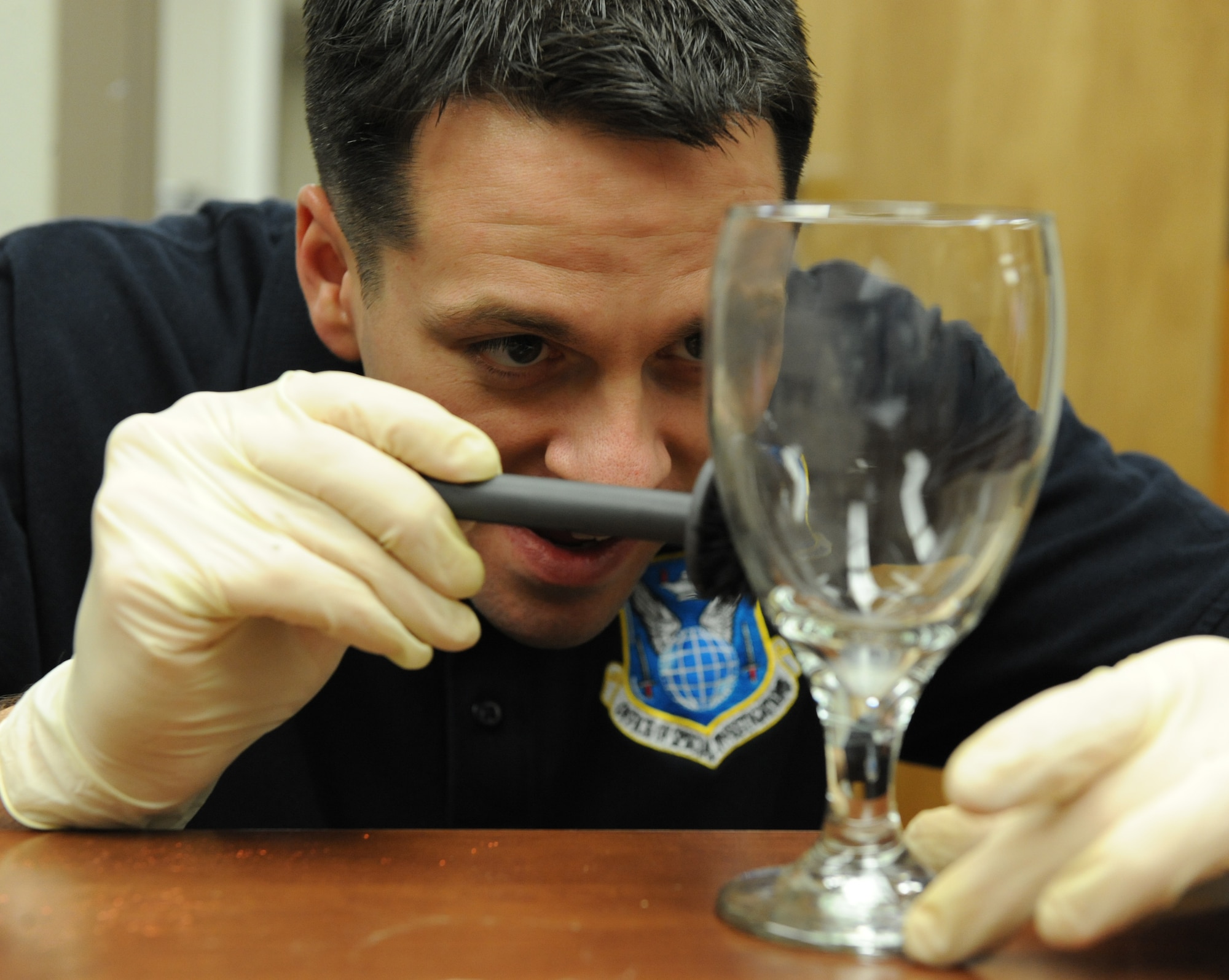 Special Agent Adam Deem, Air Force Office of Special Investigation Detachment 219, dusts a glass for fingerprints on Barksdale Air Force Base, La. Dusting for finger prints involves dusting with fine particles of the powder to adhere to residue left by skin from palms, fingers and feet. (U.S. Air Force photo by Airman 1st Class Micaiah Anthony)