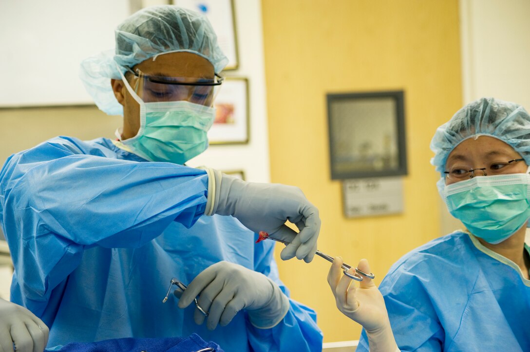 Airman 1st Class Eli Hedberg, 779th Surgical Operations Squadron otolaryngologist technician, receives a sinus tissue specimen from Dr. Carrie Flanagan, 779 SGC staff, otolaryngologist, during an endoscopic sinus surgery.  The specimen will be sent to Pathology for tissue analysis and diagnosis for Dr. Flanagan. (Air Force photo/Bobby Jones)
