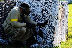 Staff Sgt. Ramon Alexander, 628th Security Forces Squadron defender, takes cover behind a barrier during a paintball match against firefighters from the 628th Civil Engineer Squadron firefighters while competing in the "Guns and Hoses" fitness challenge, May 15, 2012 at Joint Base Charleston, S.C. The 628th SFS hosted the firefighters in a day full of competition known as the "Guns and Hoses" fitness challenge. The competitions included a paintball match, defender ball and a softball game. The event kicked off National Police Week, which occurs annually during the week of May 15. It recognizes the service and sacrifice of U.S. law enforcement personnel. (U.S. Air Force photo/Staff Sgt. Nicole Mickle)