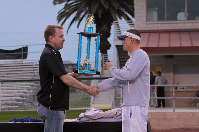 Michael A. Curtis presents Jay M. Johnson with the first place trophy during the 2012 Flag Football Championship League on Camp Pendleton, May 17. Johnson also recieved an award for Coach of the Year. Curtis is a sports coordinator with Marine Corps Community Services Athletics. Johnson is the coach for Combat Logistics Regiment 17 Desk Jockeys.