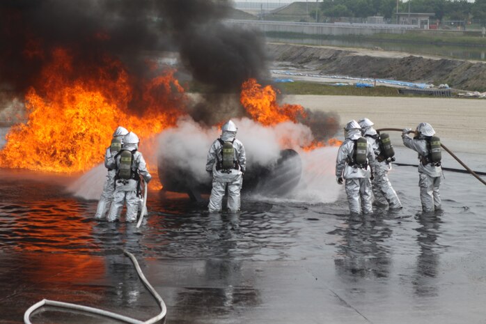 Station Aircraft Rescue Firefighting Marines battle a blaze as training during a job shadow day with students from Matthew C. Perry High School at the ARFF fire pit training area here May 17, 2012. The students spent the day following ARFF Marines as they went about the daily routine involved with being ARFF Marines.