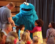 Cookie Monster, a philosophical Muppet who now enjoys cookies in addition to a well-balanced diet, comes out to greet Marine families during a USO performance of Sesame Street Live aboard Marine Corps Air Station New River, April 28. During the show, Cookie Monster gave advice to Marine families about moving away from friends.